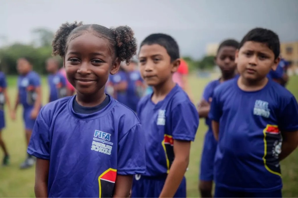 Children wearing FIFA Football for Schools t-shirts on a football field