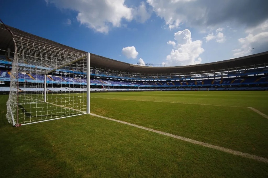 A modern football stadium with a goalpost on the pitch under a blue sky