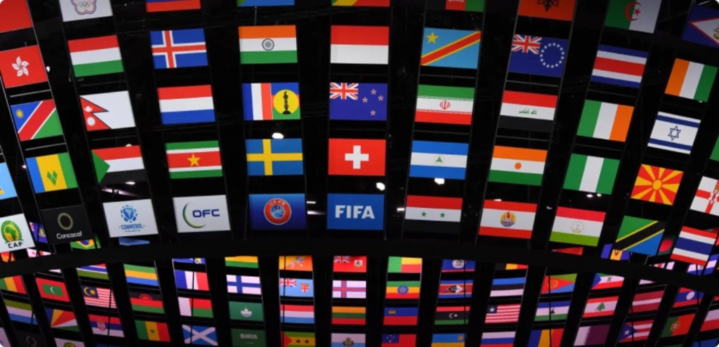 FIFA and confederation logos with national flags displayed on a curved wall